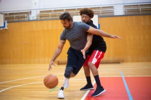 Two men playing basketball indoors showcasing inclusive sports and teamwork.