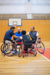 Group of men in wheelchairs playing basketball indoors, showcasing teamwork and sportsmanship.