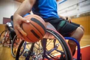 Close-up of an athlete with a basketball in a wheelchair during a game in a sports hall.
